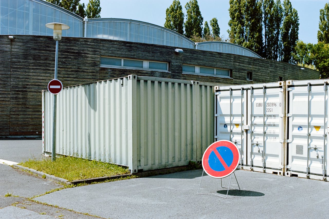 Two storage containers with traffic signs in an industrial area on a sunny day.