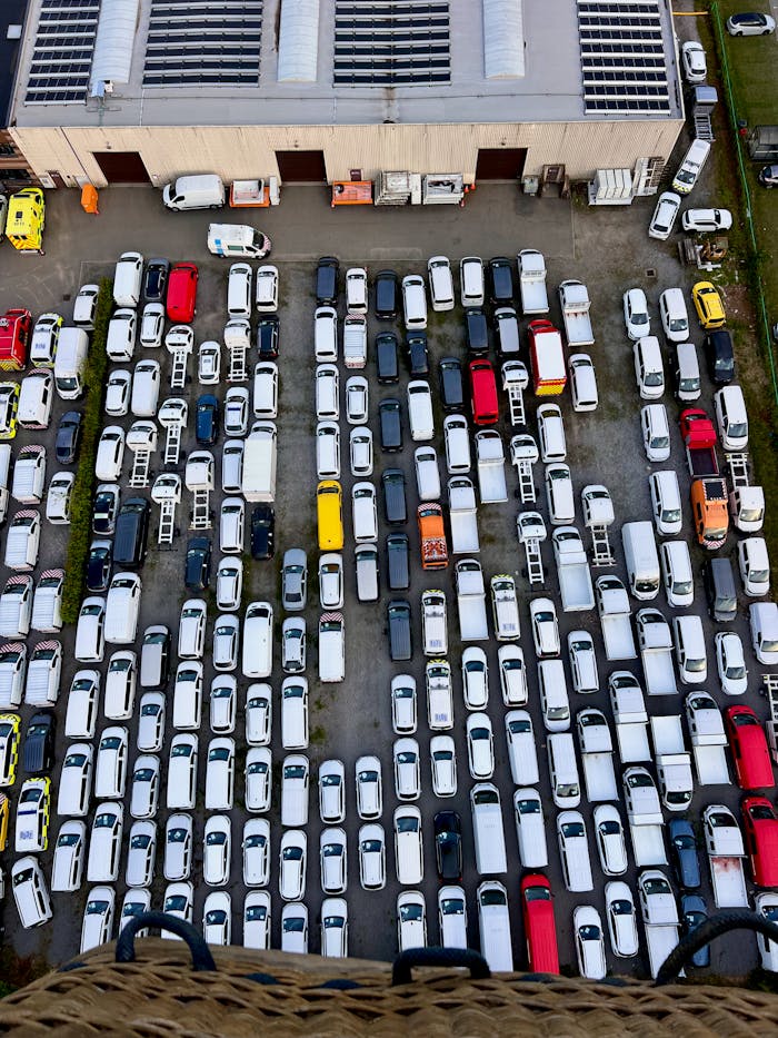 Top view of an organized parking lot filled with multiple vehicles of various colors.